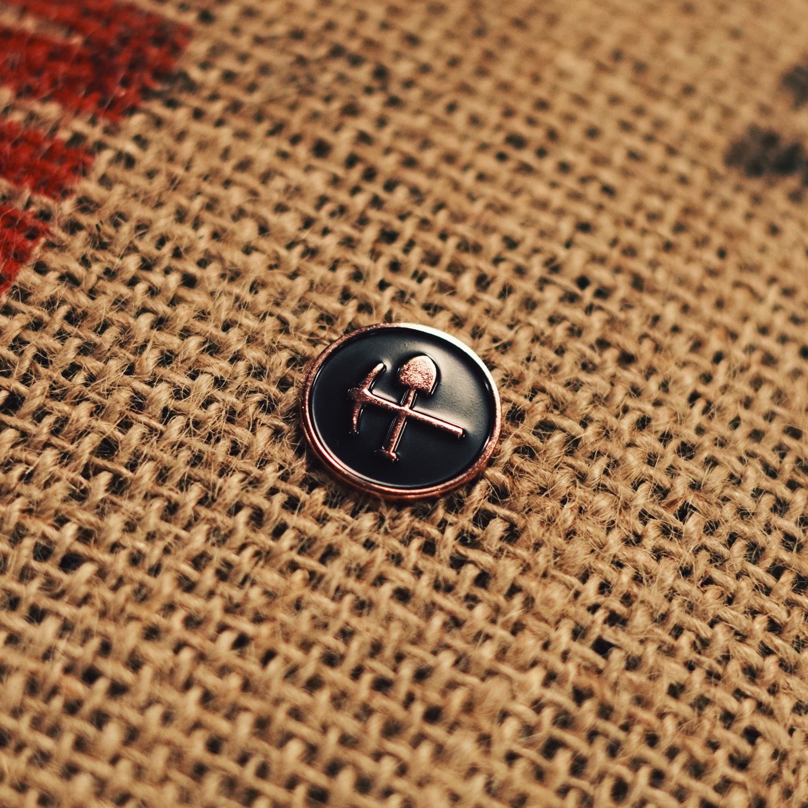 A polished stamped copper pin with black enamel inlay, with Coaltown pick and shoval