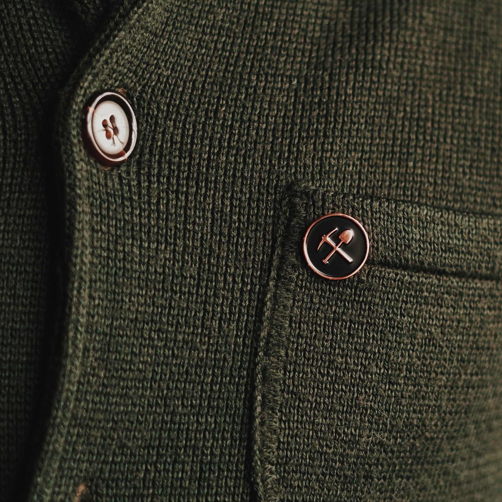 A polished stamped copper pin with black enamel inlay, with Coaltown pick and shoval