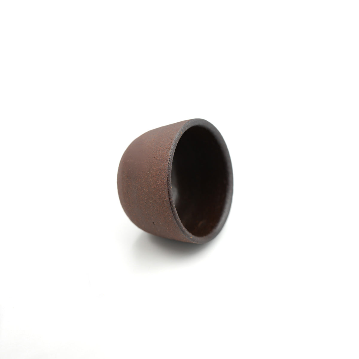 A small dark brown ceramic cup with a textured matte exterior and a glossy dark interior, shown on a plain white background.