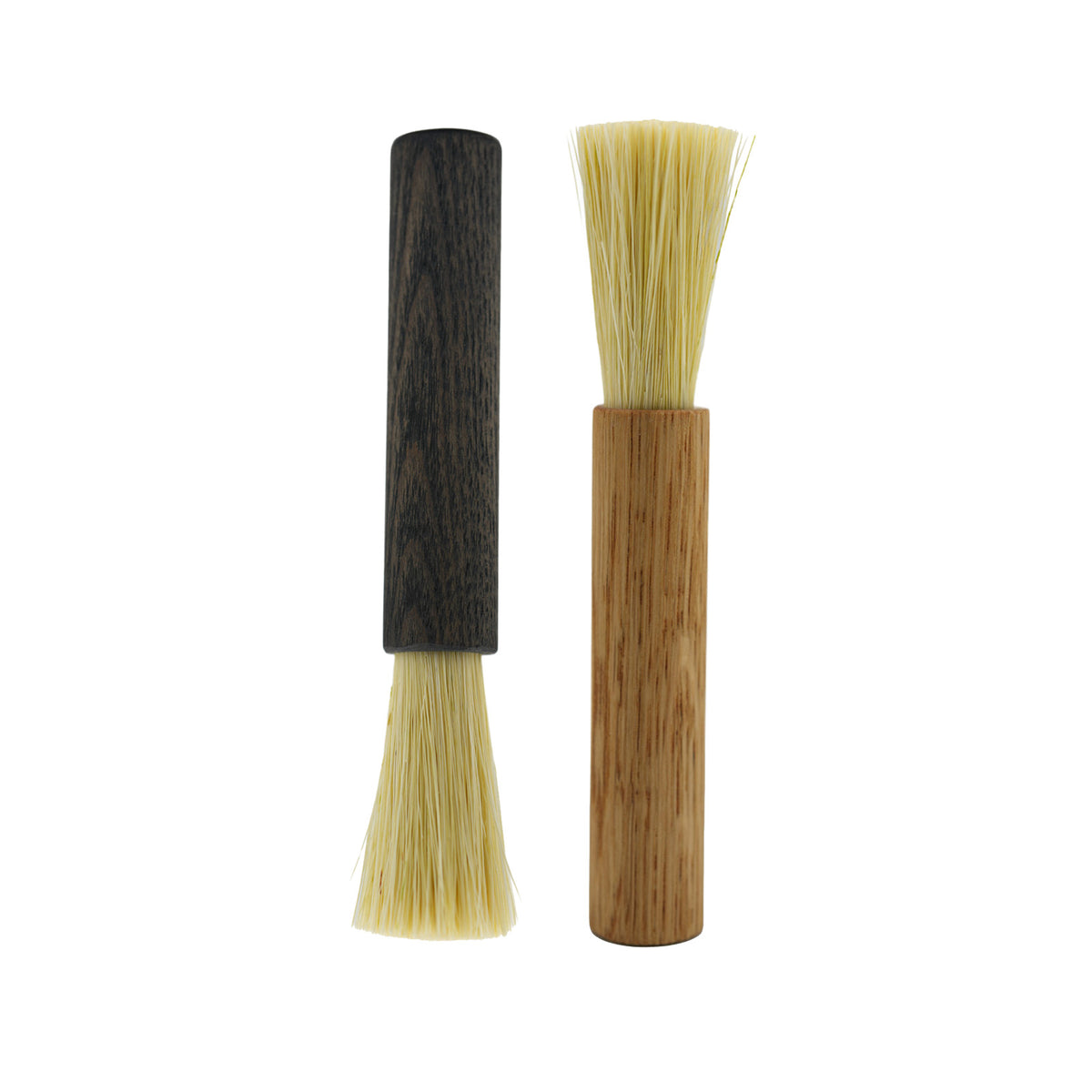 Two small coffee brushes with natural bristles, one featuring a dark wood handle and the other a light wood handle, shown on a plain white background.