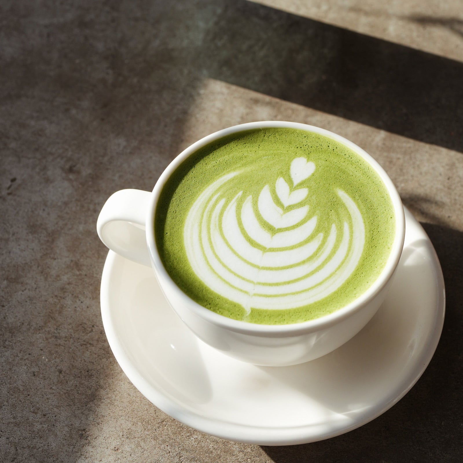 white mug of hot green matcha with milk art